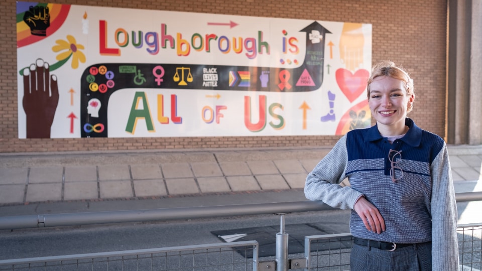 Student stood in front of inclusive art mural