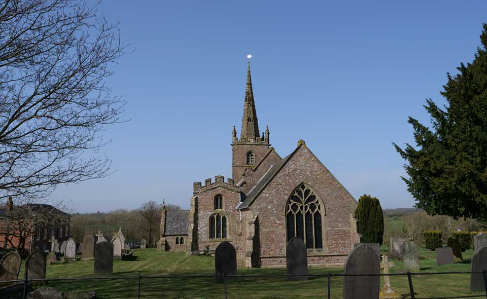 A traditional stone built country church surrounded by a grassed graveyard and stone headstones