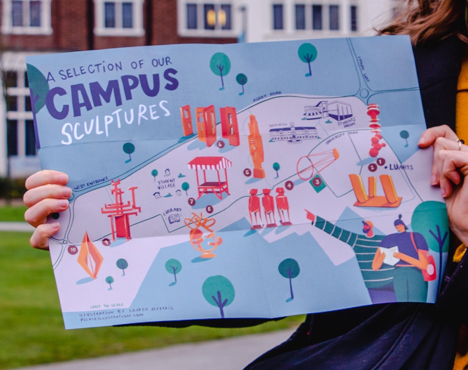 Our A3 Lu Arts sculpture map being held up in front of Hazelrigg fountain