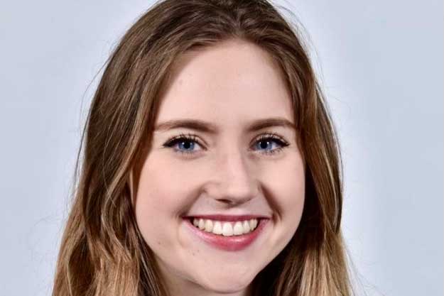 Headshot of a white female , smiling with long medium brown hair and blue eyes. 