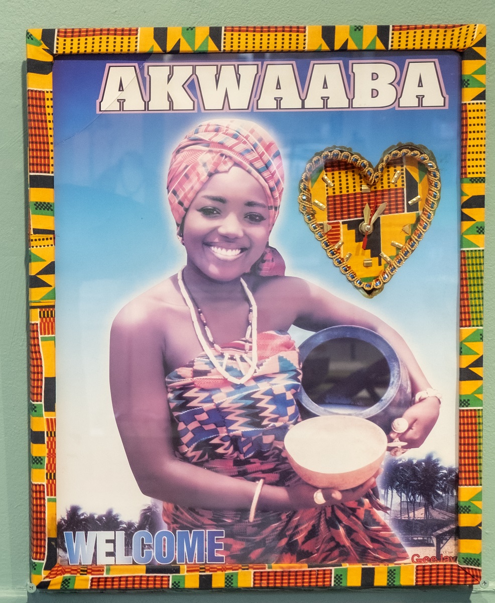 A smiling black woman with the word Akwaaba and welcome on a framed poster