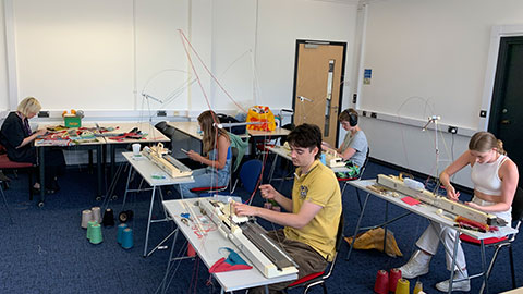 Student sitting in front of knitting machines