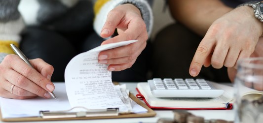 hand holding a pile of bills with calculator