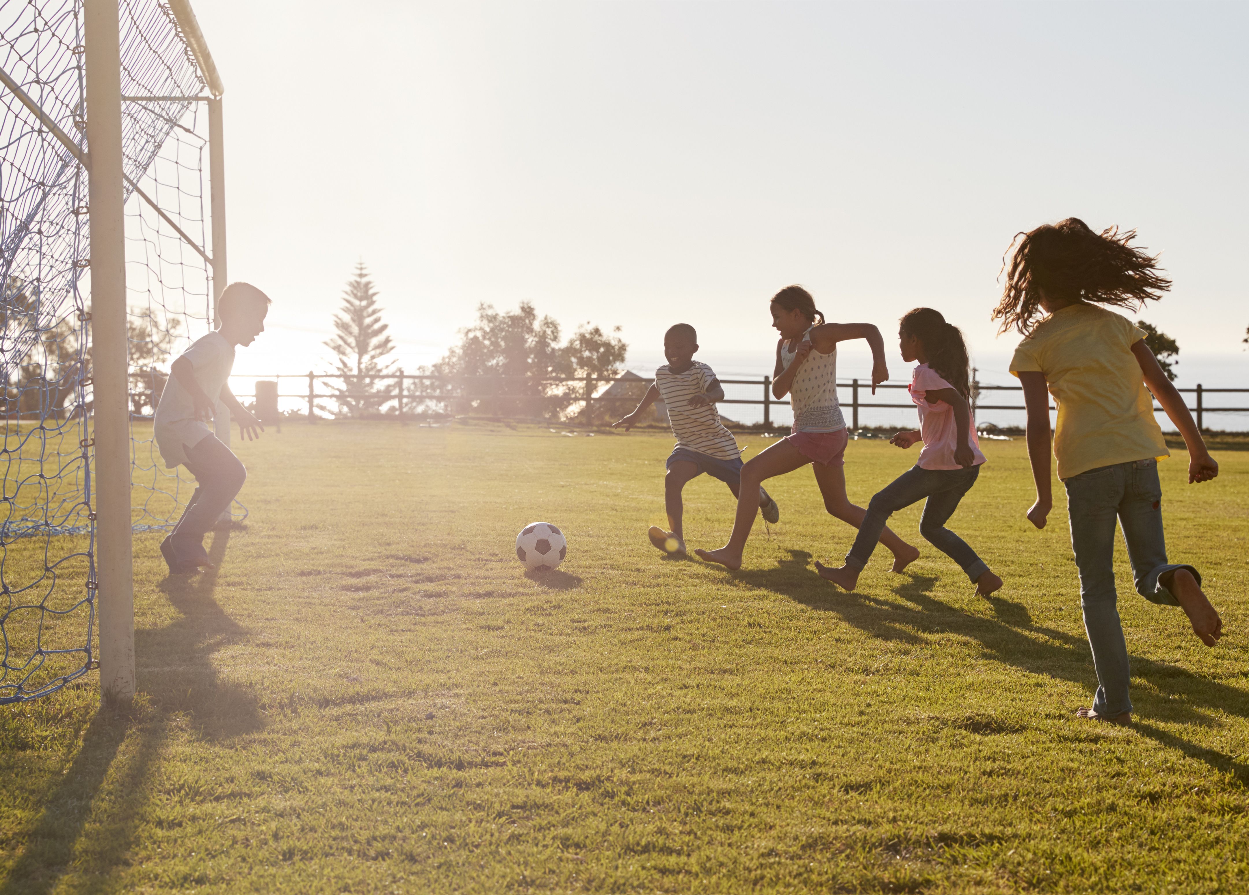 Children playing football in the sunshine