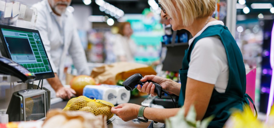 A man stands at a check queue in a supermarket while the cashier scans his lemons