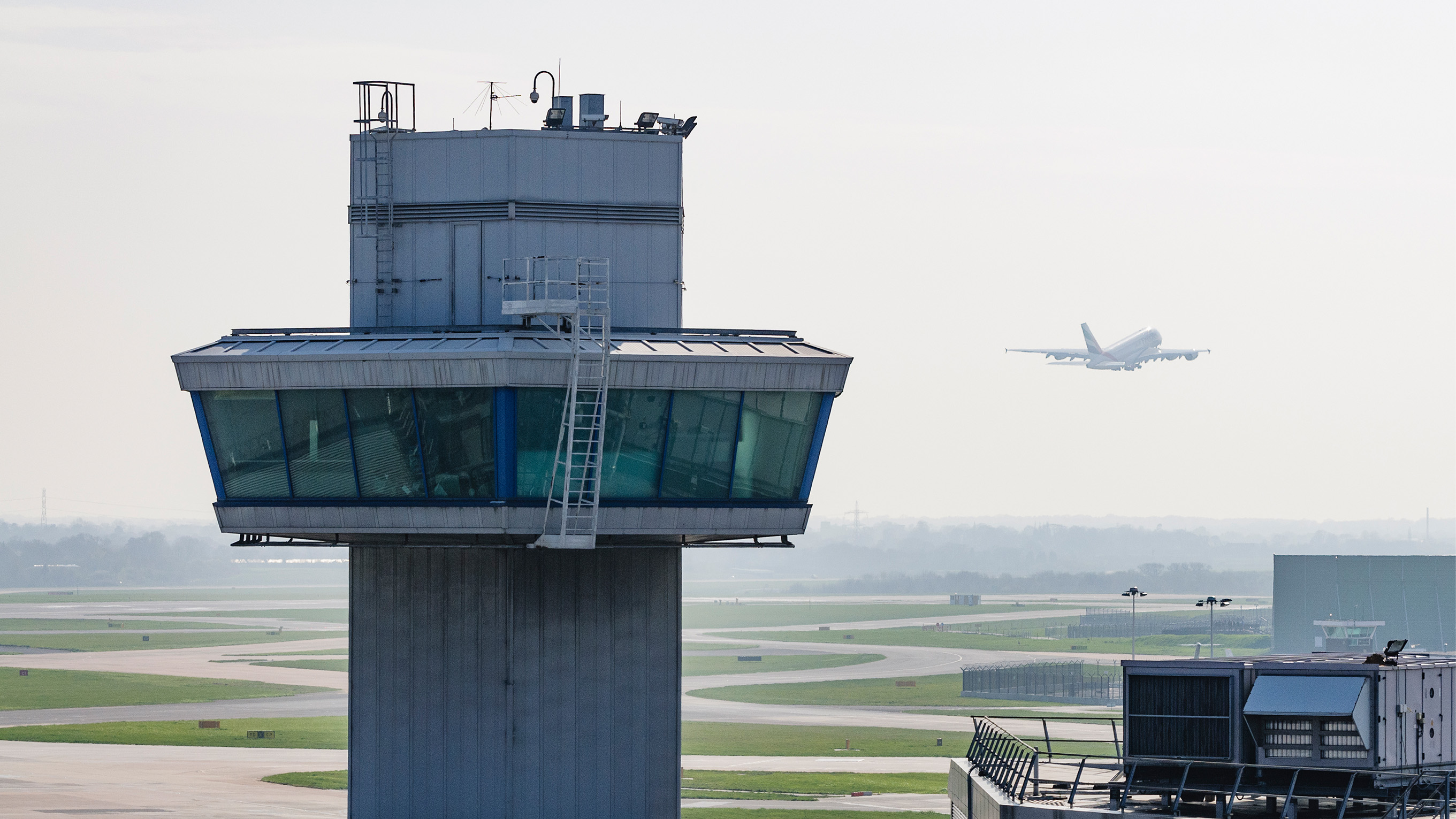 air traffic control tower and plane taking off in background