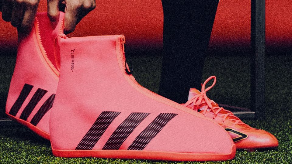 Someone is about to put on adidas’ CLIMACOOL SYSTEM overshoe. This is a pink textile boot with three black stripes on the side