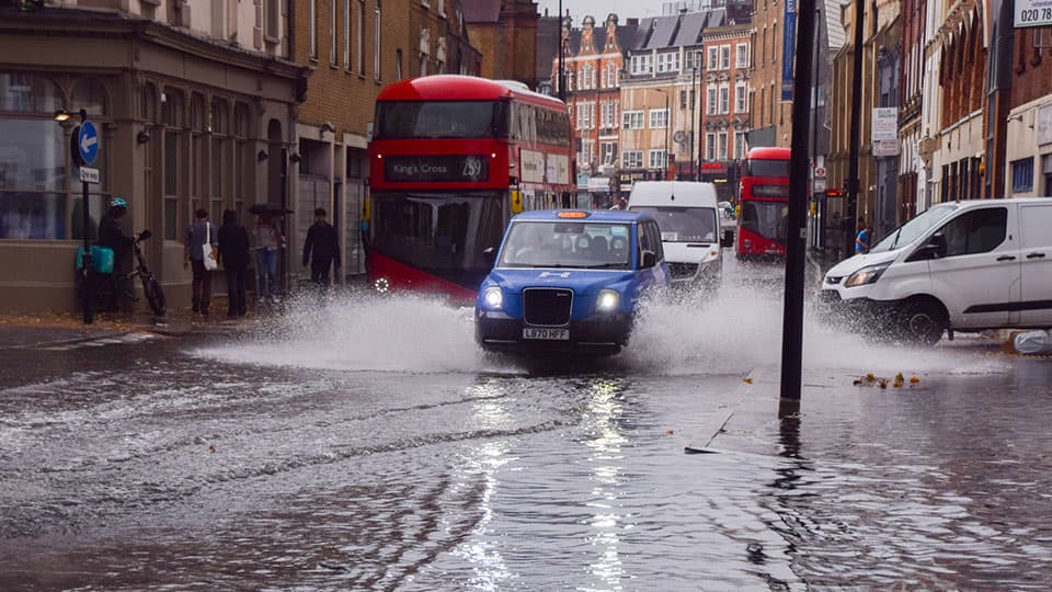 Buses, taxis, and vans driving through flood water in London