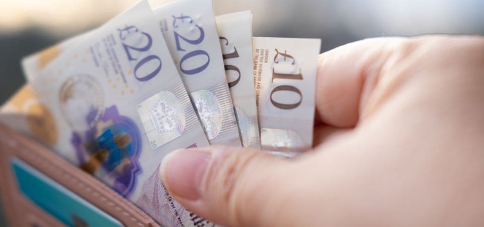 A person pulling bank notes out of a purse.