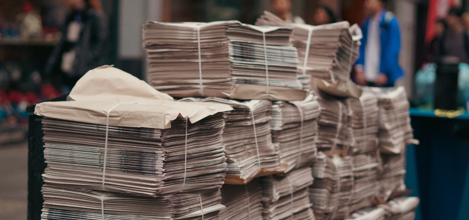 Piles of newspapers sit untouched