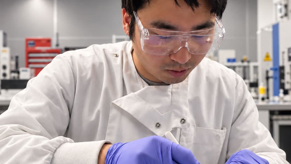 A scientist in a lab wearing gloves and goggles