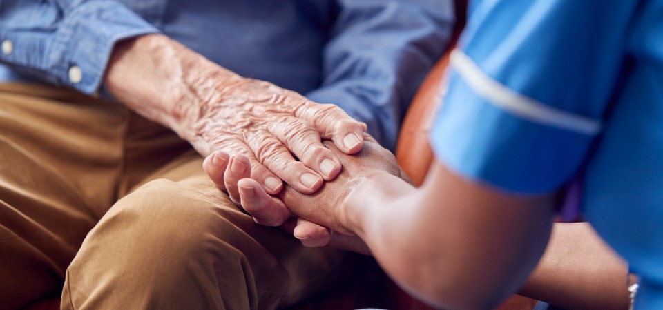 an elderly person holds hands with a nurse