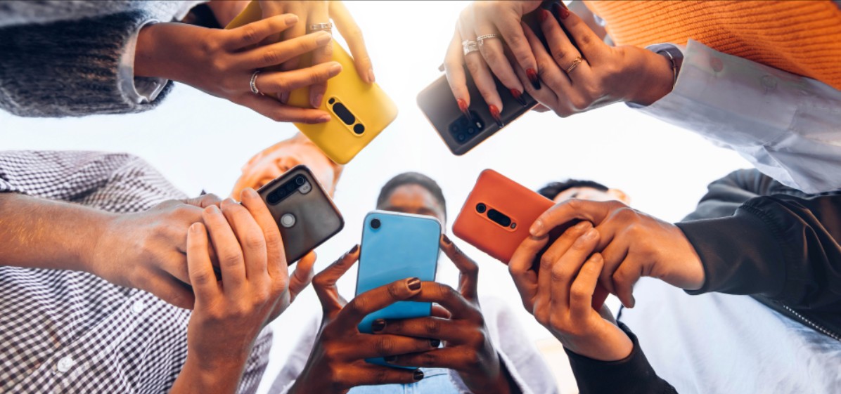 teens stand in a circle ooking at their phones