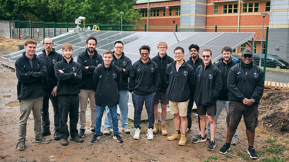 A group of students stood in front of a solar panel