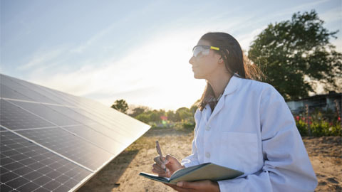 Woman working in solar energy, writing research on solar panels in summer.