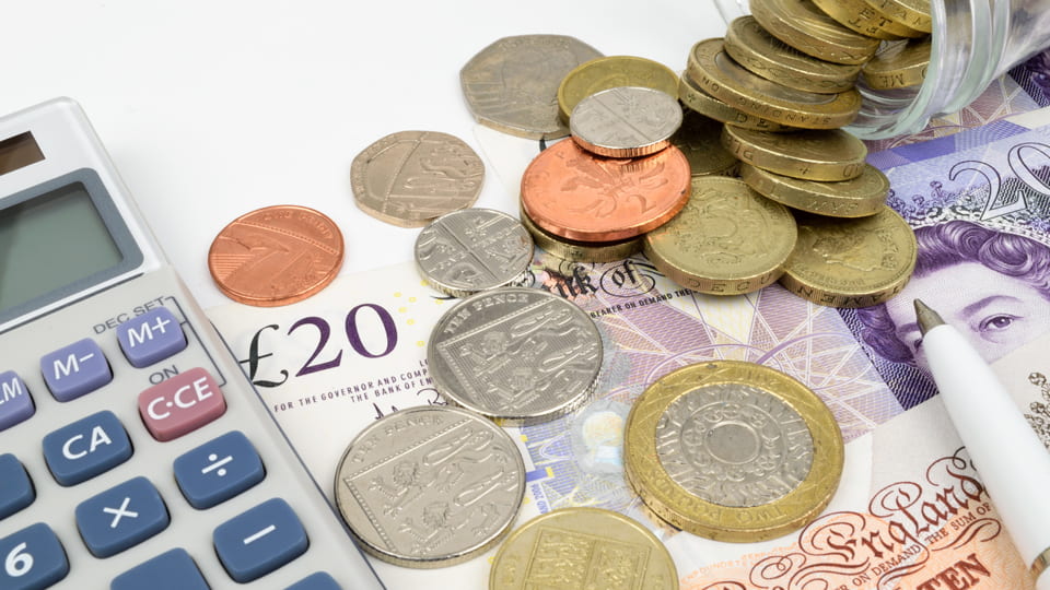 A calculator, £20 note and a selection of coins.