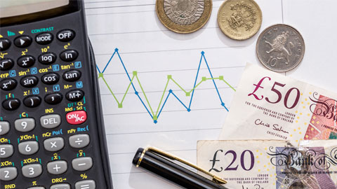 British currency on fluctuating graph with calculator and pen.
