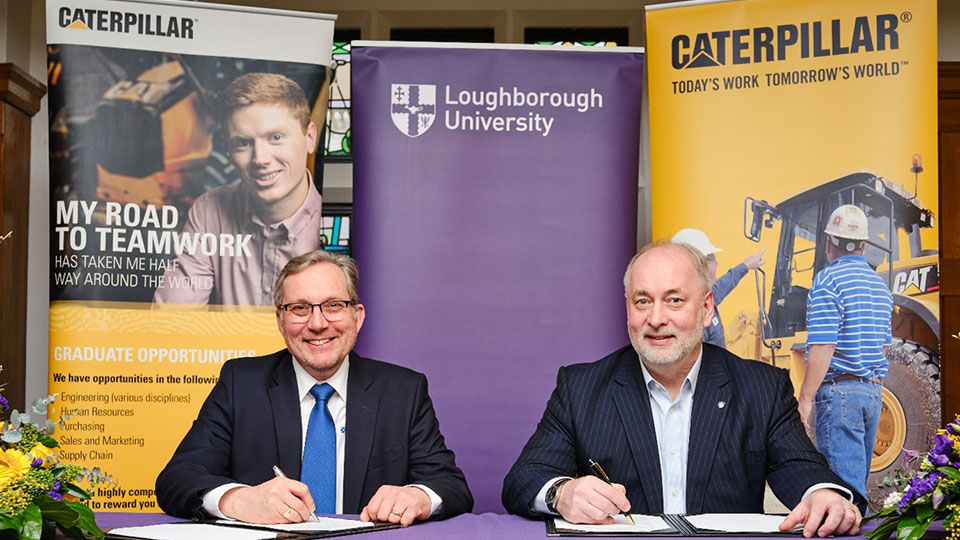 David Goldpink and Professor Nick Jennings sitting at a table signing papers with banners in the background.