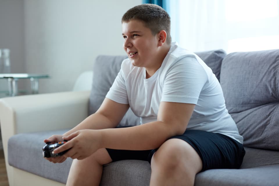 A teenage boy sits on a sofa playing with a video game controller