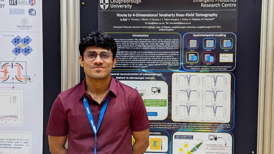 A man stands in front of a scientific research poster about terahertz near-field tomography at a conference display.