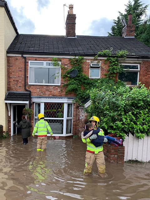 fireman rescuing a family from a flooded house