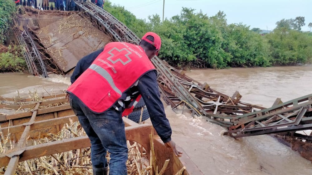 floods in kenya - a man in emergency services vest next to a collapsed bridge
