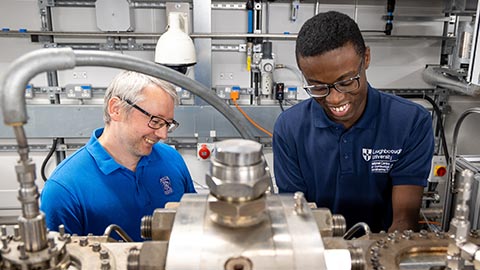 Two male researchers from the Rolls-Royce University Technology Centre standing working on an engine