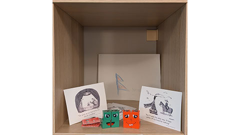 Colourful cubes with faces on, satirical postcards and a childs drawing of the Nepal flag