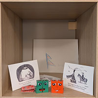 Colourful cubes with faces on, satirical postcards and a childs drawing of the Nepal flag