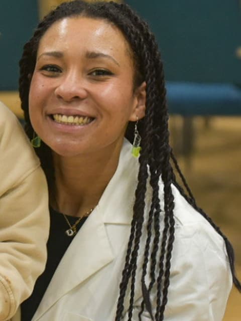 Naomi smiles wearing a white suit jacket