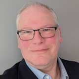 Professional headshot of Neil in a suit and glasses