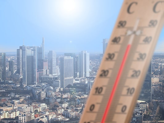 City scene showing high temperature on thermometer