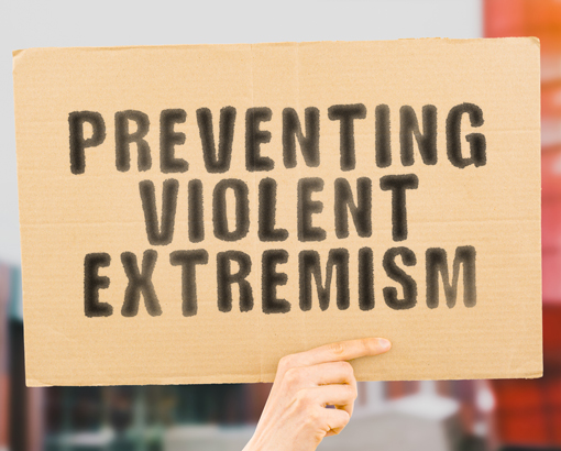 Hand holding up a placard that reads: Preventing violent extremism