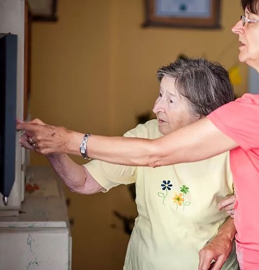 Photograph of a woman helping an older person to use smart home technology