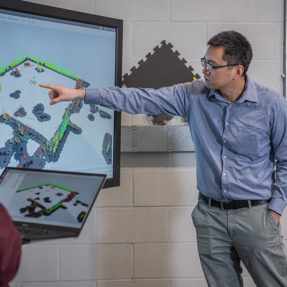 Cunjia Liu pointing to and discussing a computer simulation of his technology