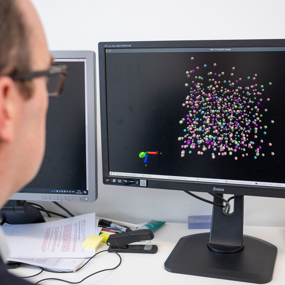 Looking over Jamieson's shoulder at a model of a sulfide glass on his computer screen