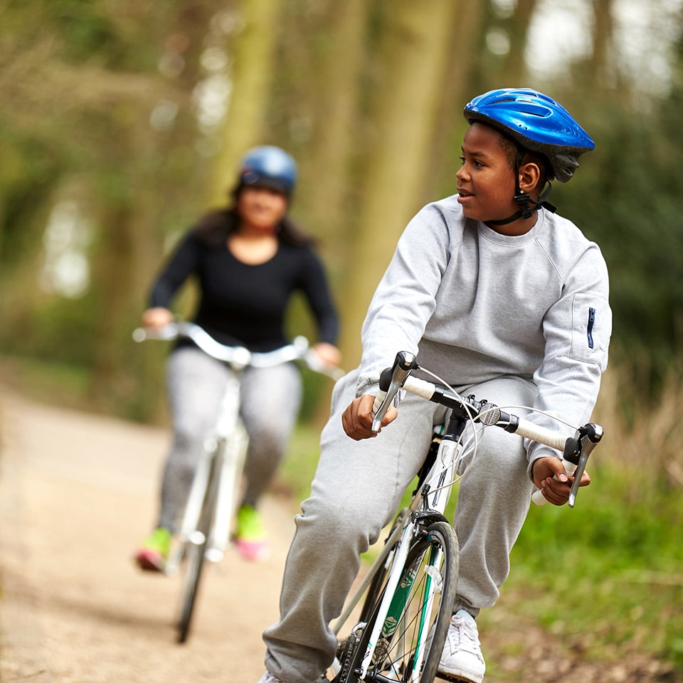 Boy and Mum riding bikes in the woods. Image credit: World Obesity Federation.