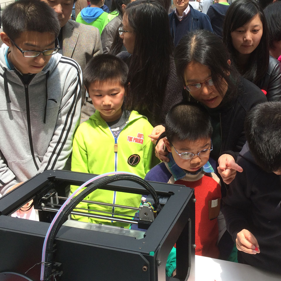 Children inspect a 3D printer during an open day