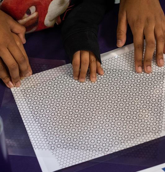 Close-up shot of two sets of hands (adult helping child), building a kaleidoscope