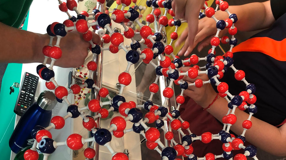 Close-up shot of students working with a ball and stick model