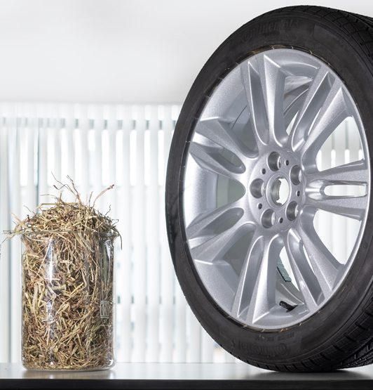 A beaker of straw beside a car tyre