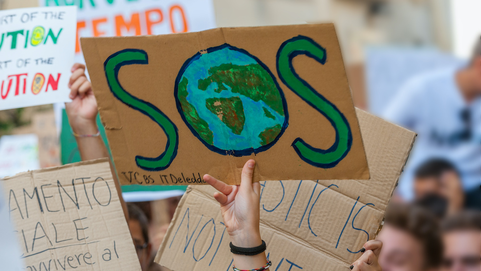 home made banners at a climate protest, the nearest one has a SOS with earth in the middle