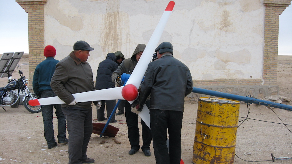 a group of people carrying a wind turbine