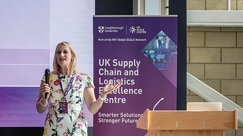 A person presenting in front of a UK Supply Chain and Logistics Excellence Centre banner