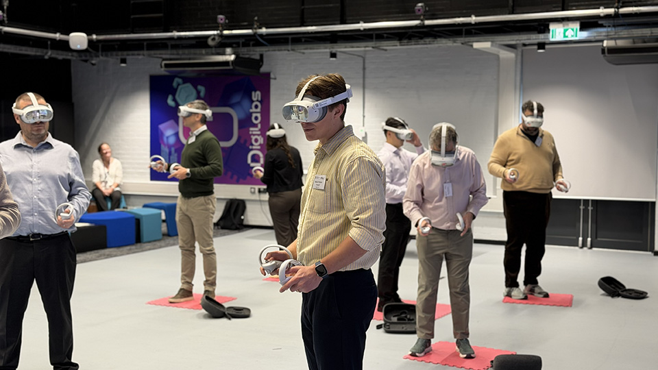 Retreat delegates wearing virtual reality headsets and using handheld controllers during an interactive DigiLab leadership exercise.