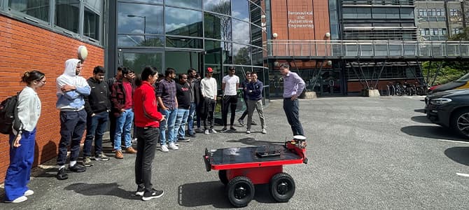 students stood outside the stuart miller building with robot