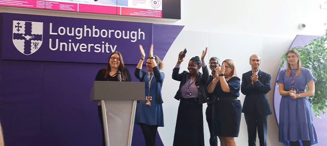group of academics on stage raising their hands in the air and clapping at an event