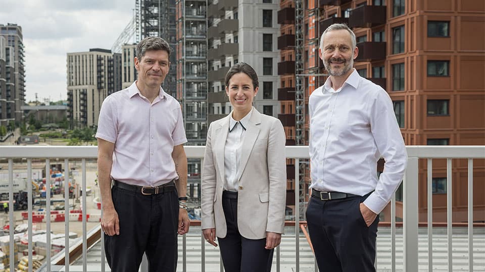 three people standing in front of a building site