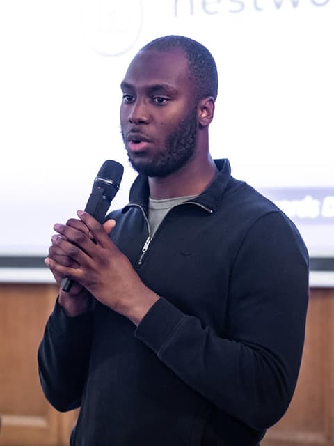 Samuel Ola speaking into a microphone.