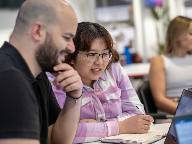 Two students working together in a study space.